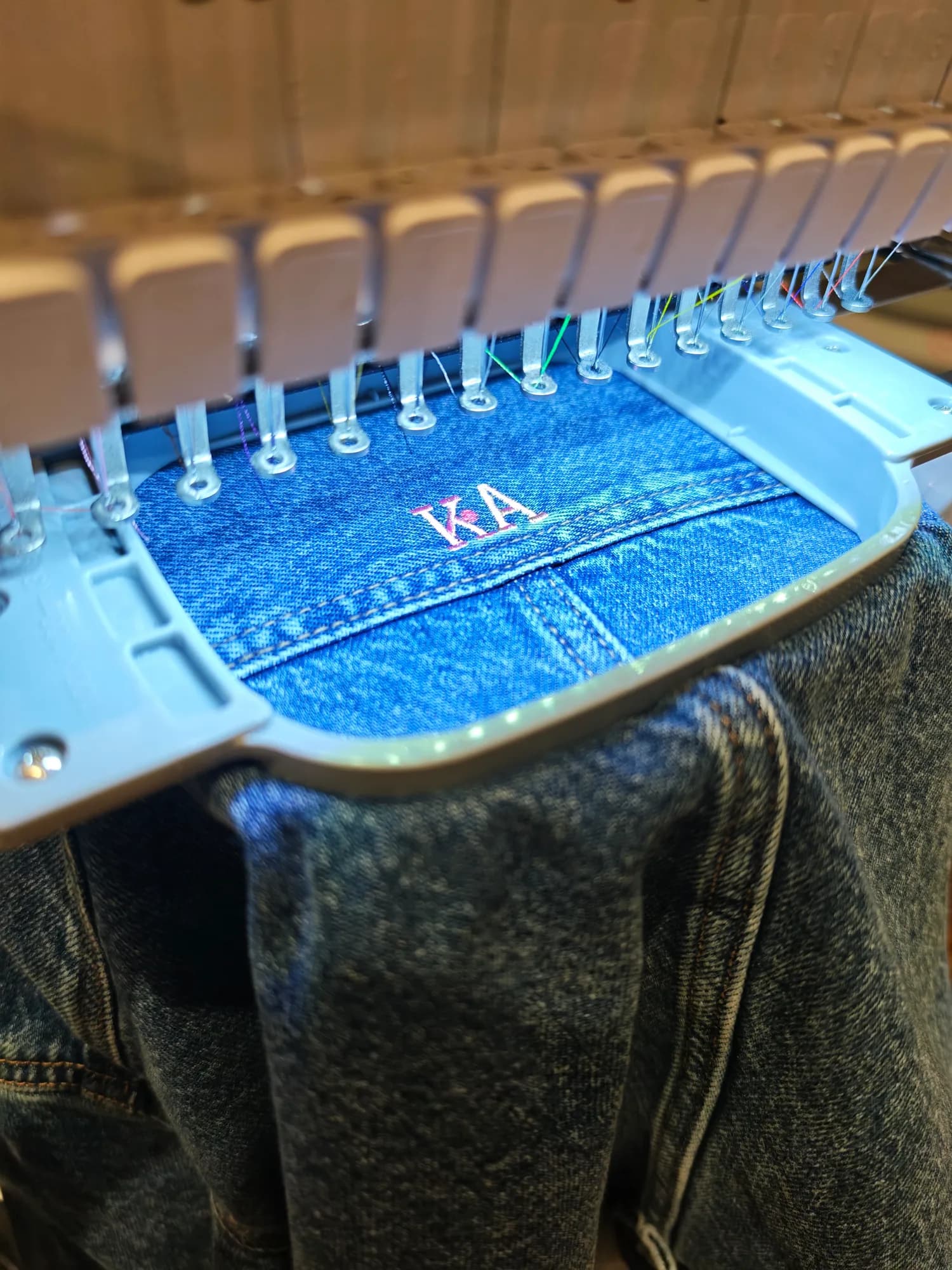 Close-up of pink initials being embroidered onto River Island denim