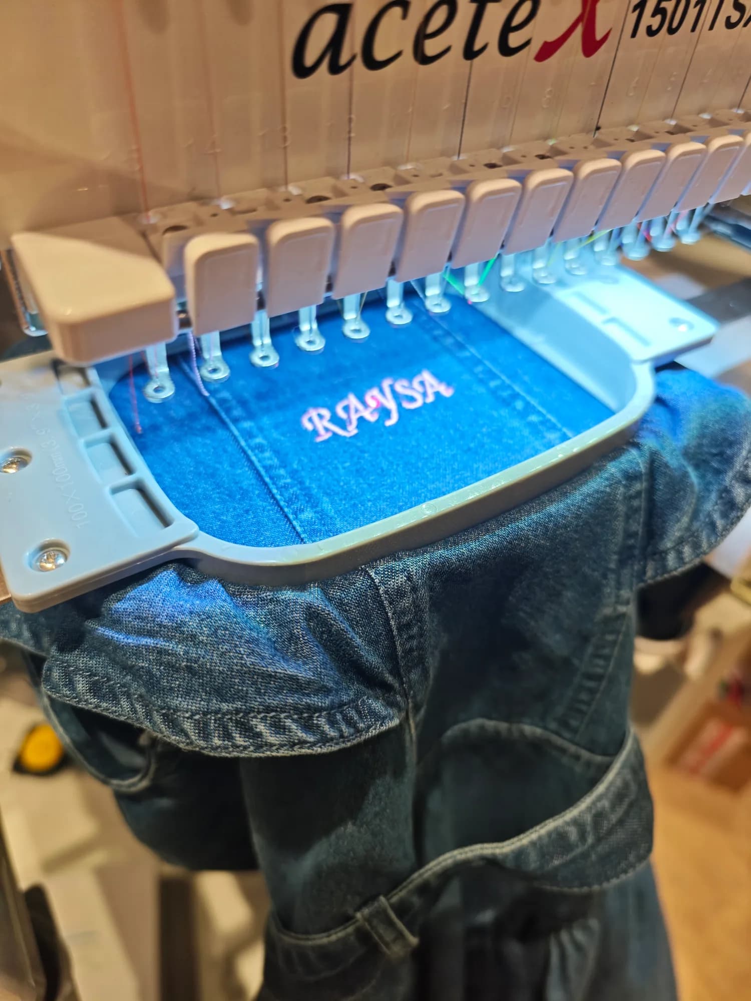 Initials being embroidered onto blue River Island jeans during a retail activation