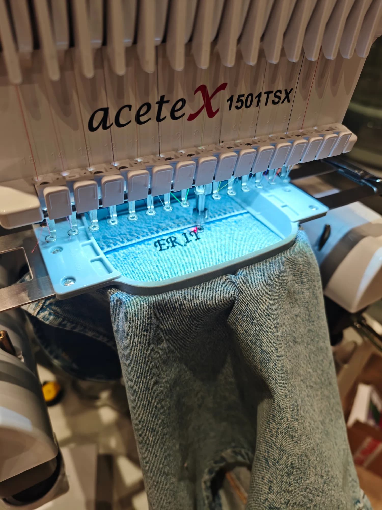 Professional embroidery machine stitching initials onto River Island denim at Bullring